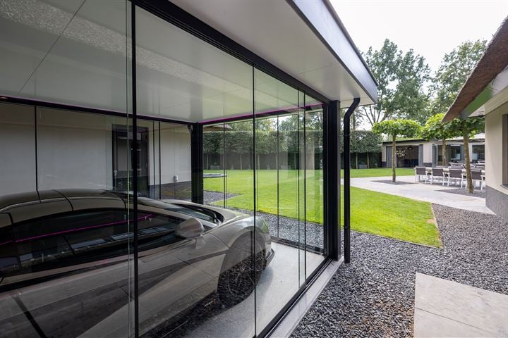 Glazen showcase garage waar een grijze McLaren instaat.